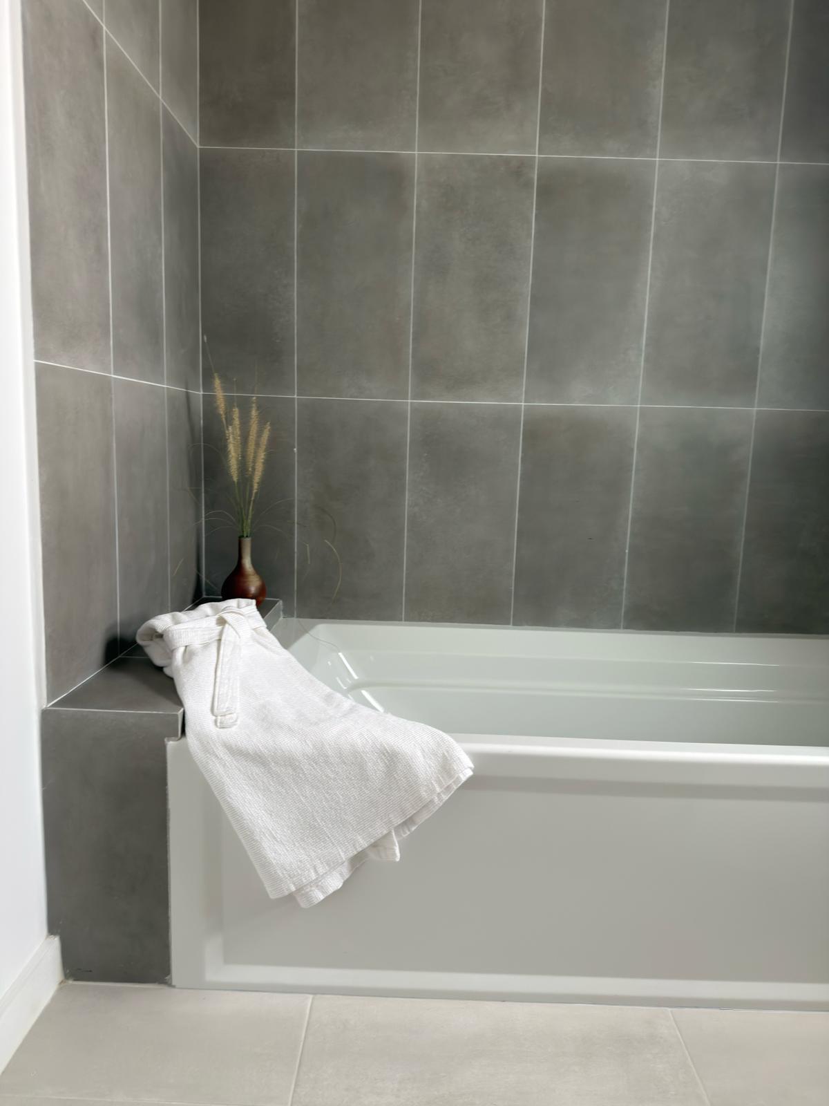 Modern apartment bathroom with bathtub and large grey wall tiles
