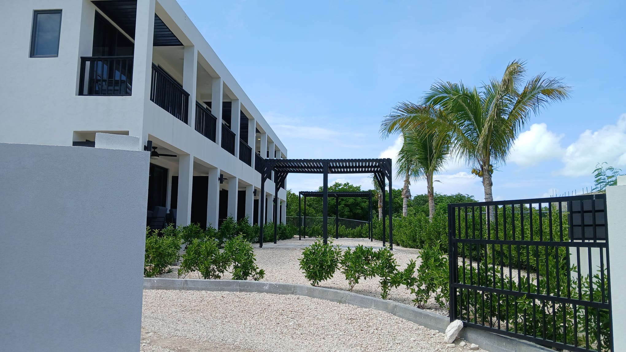 Landscaped apartment courtyard with pergolas, palm trees and secure entrance gate