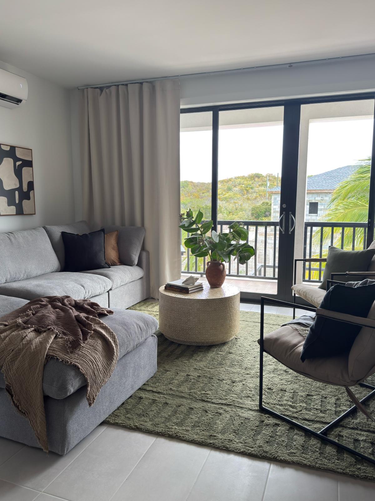 Bright apartment living room with a grey sectional sofa and balcony access